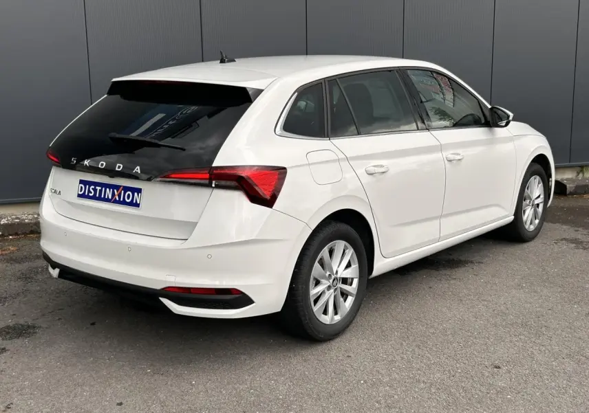 Vue 3/4 arrière droite d'une Skoda Scala blanc Candy avec vitres arrière surteintées et jantes alliage 16 pouces.