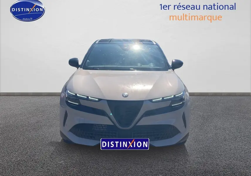 Vue frontale d'une Alfa Romeo Junior 1.2 hybride 2026 ivoire et noir avec phares matrix LED allumés.