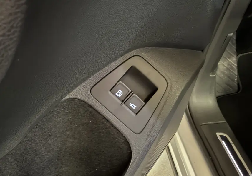 Boutons d'ouverture de la trappe à carburant et du coffre sur le côté gauche intérieur d'un Volkswagen Tiguan gris clair 2022.