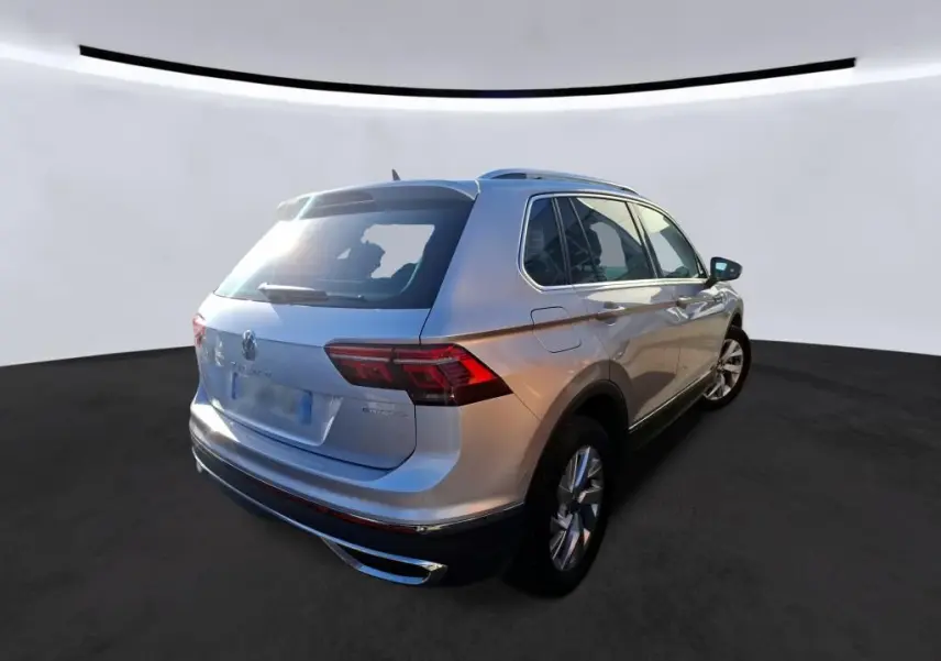 Vue 3/4 arrière droite d'un Volkswagen Tiguan gris clair 2022 hybride rechargeable avec feux arrière LED et toit ouvrant.