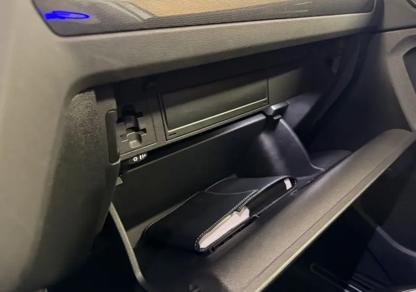 Vue rapprochée de la boîte à gants ouverte du Volkswagen Tiguan gris clair 2022, avec un carnet noir à l'intérieur.