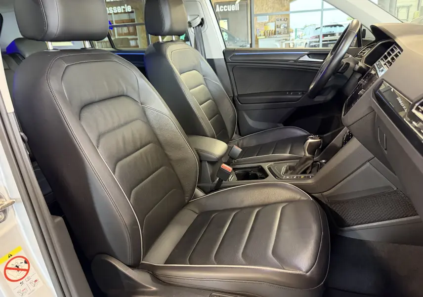 Vue intérieure côté gauche du Volkswagen Tiguan 1.4 E-HYBRID 2022, sièges avant en cuir noir et console centrale visible.