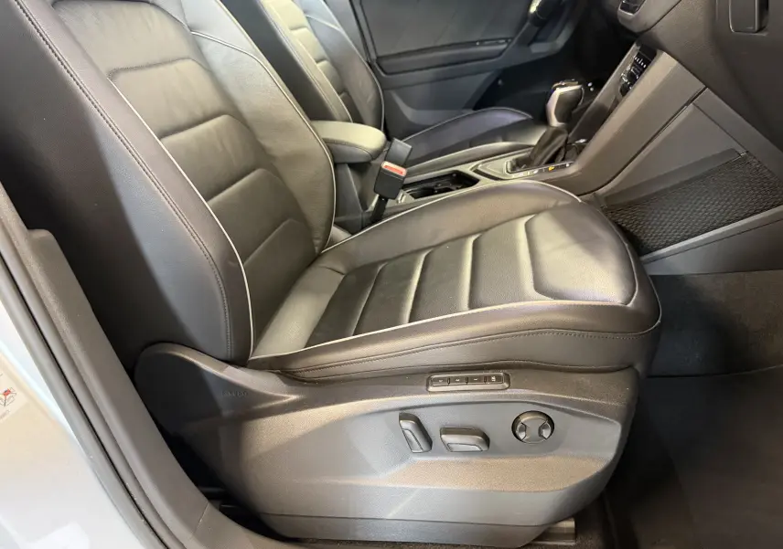 Vue intérieure côté conducteur du Volkswagen Tiguan 1.4 e-Hybrid 2022, sièges en cuir noir avec réglages électriques.