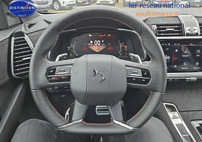 Vue rapprochée du volant cuir DS noir avec commandes intégrées et tableau de bord numérique du DS7 2025.