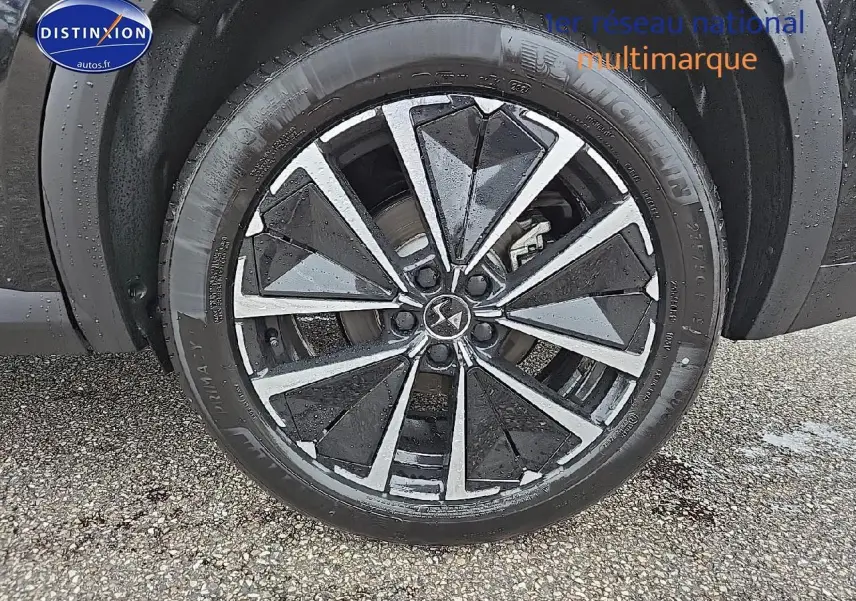 Gros plan sur la jante alu noire et argent du DS7 1.5 BlueHDi 130 Pallas noir, roue avant droite sous la pluie.