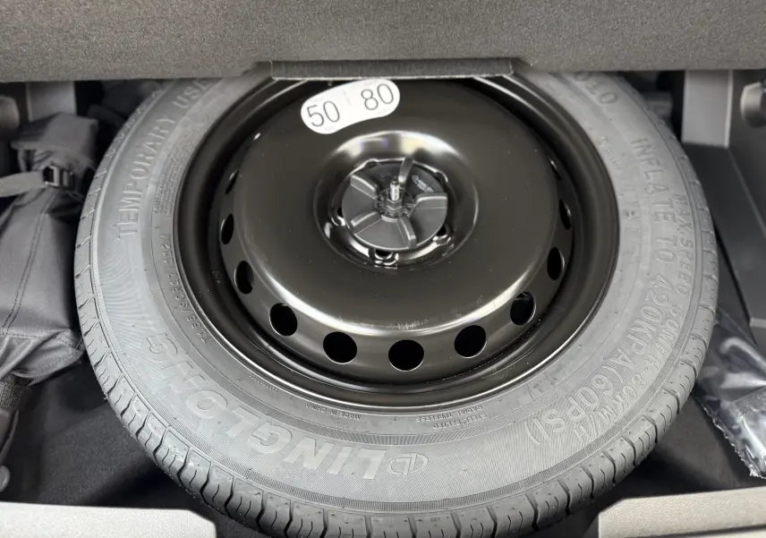 Gros plan sur la roue de secours noire dans le coffre du Renault Austral 2025 hybride bleu Iron toit noir.