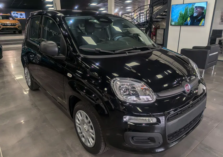 Vue 3/4 avant droite d'une Fiat Panda 2025 noire, compacte et brillante, exposée en showroom moderne.