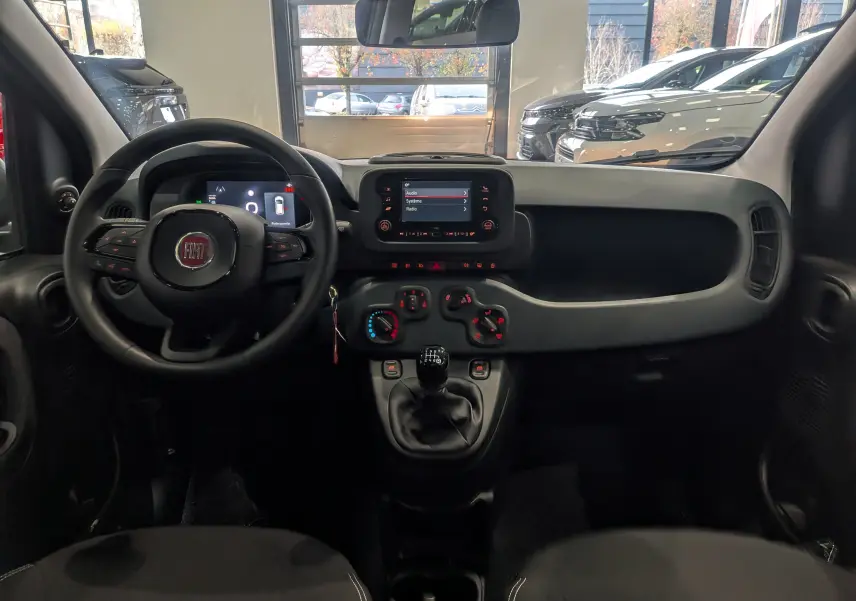 Vue intérieure avant du tableau de bord et volant noir de la Fiat Panda 1.0 Hybrid City 2025 avec écran tactile et commandes manuelles.