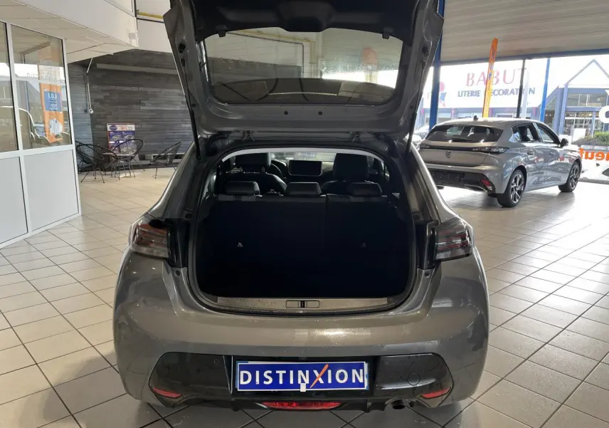 Vue arrière ouverte d'un Peugeot 208 gris clair Selenium en concession, avec feux arrière à LED et intérieur visible.