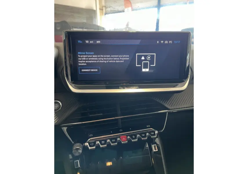 Vue intérieure du tableau de bord de la Peugeot 208 2024, écran tactile et commandes centrales en finition carbone.