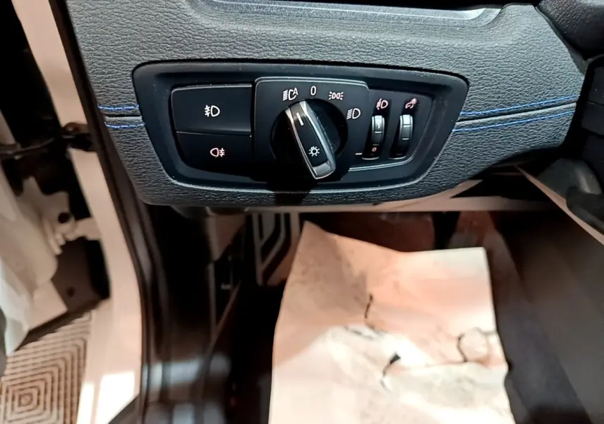 Détail du panneau de commande des phares sur la gauche du tableau de bord d’un BMW X1 blanc 2022.