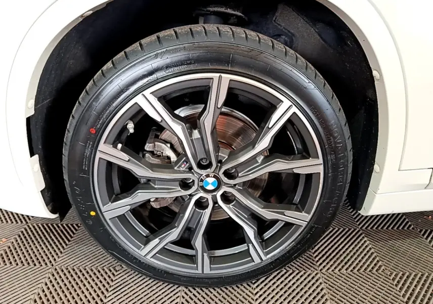Gros plan sur la roue avant droite d’un BMW X1 blanc, jante alliage M Sport à design moderne et logo BMW central.