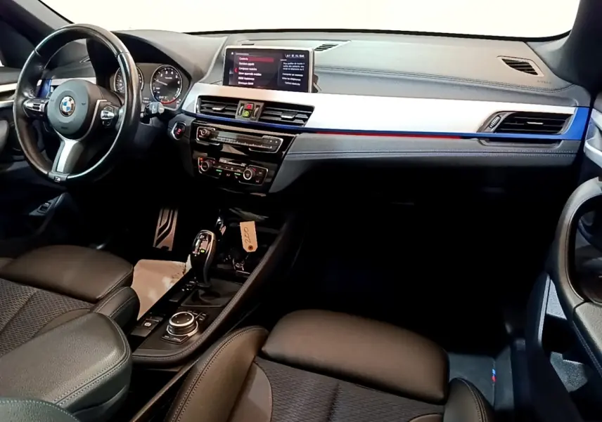 Vue intérieure avant de la BMW X1 sDrive18i M Sport 2022, tableau de bord avec écran tactile 8,8 pouces et volant cuir multifonctions.