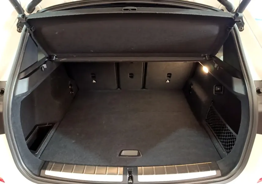 Coffre ouvert vu de l'arrière d'un BMW X1 blanc 2022, avec intérieur noir et éclairage latéral allumé.