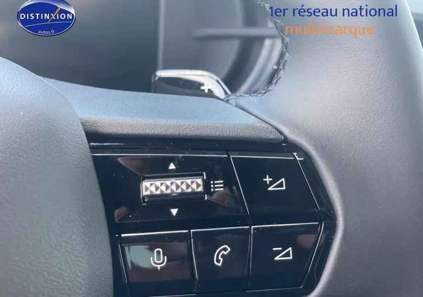 Gros plan sur les commandes multifonctions noires au volant de l'Alfa Romeo Junior gris, avec molette et boutons tactiles.