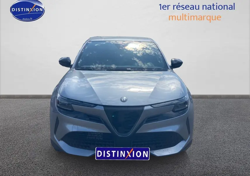 Vue frontale d'une Alfa Romeo Junior 1.2 hybride gris métallisé avec calandre triangulaire distinctive et phares fins.
