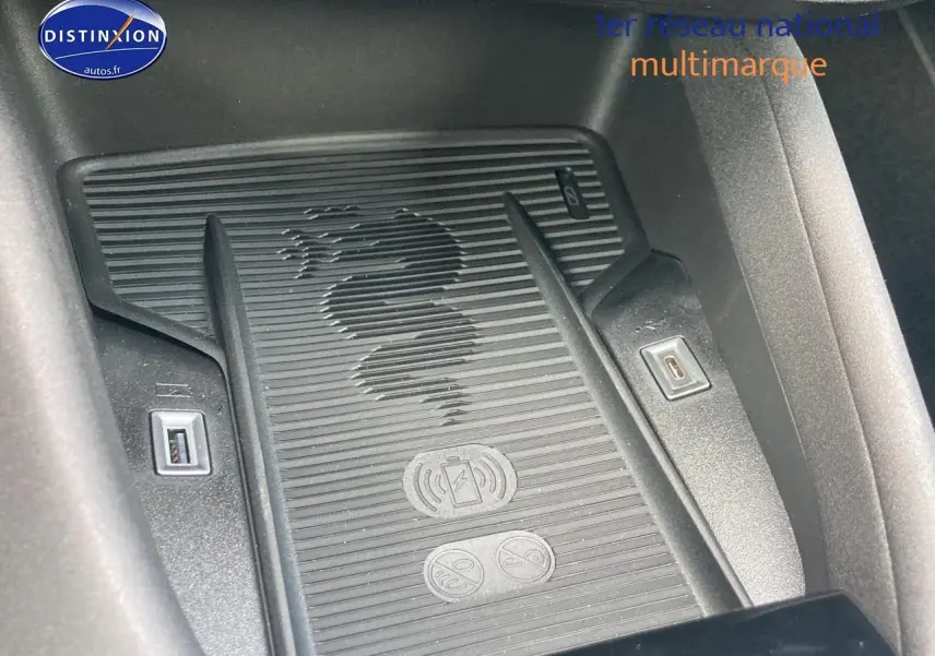 Gros plan sur la zone de charge à induction avec logo Alfa Romeo, entourée de ports USB, intérieur noir.