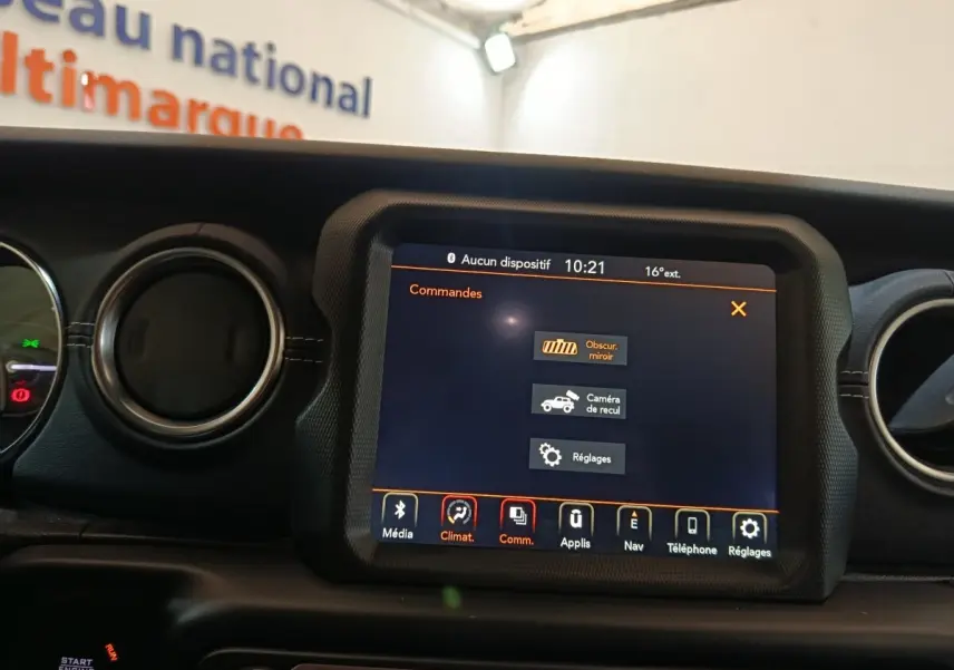 Vue rapprochée de l’écran tactile central du tableau de bord du Jeep Wrangler gris foncé, affichant les commandes multimédia et réglages.