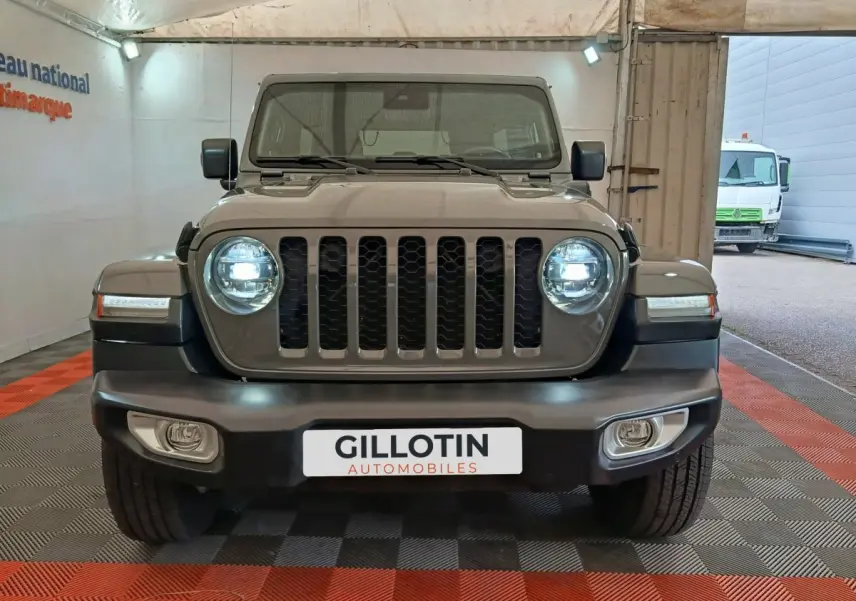 Vue frontale d'un Jeep Wrangler gris foncé avec phares LED allumés et calandre à sept barres verticales.