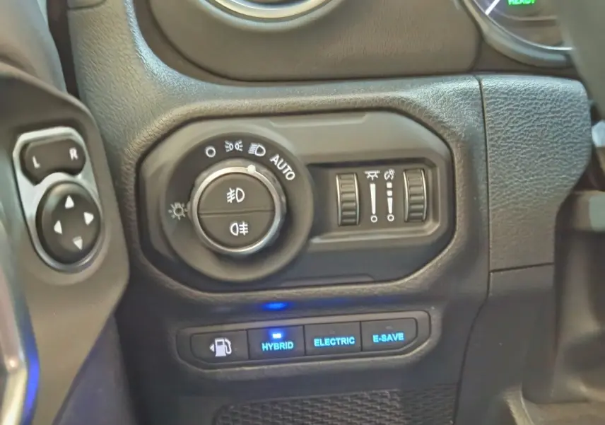 Gros plan sur les commandes d’éclairage et modes hybride du tableau de bord d’une Jeep Wrangler 2022.
