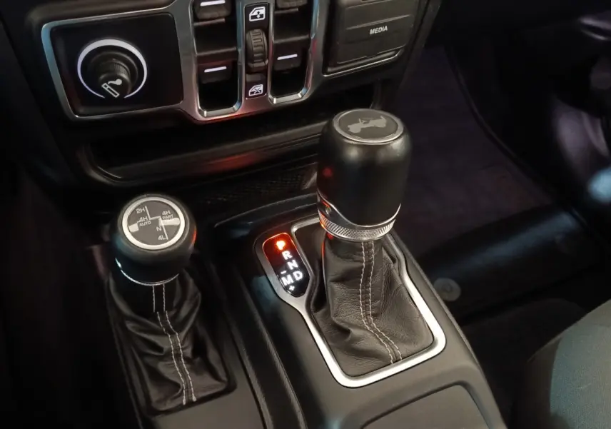 Gros plan sur le levier de vitesses automatique et la commande 4x4 du Jeep Wrangler gris foncé, intérieur noir.