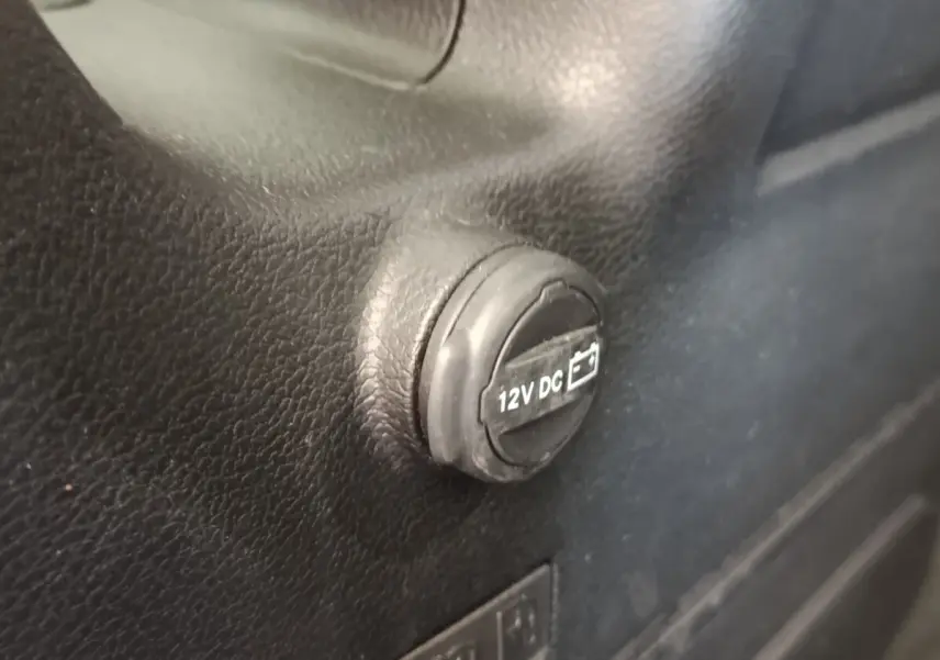 Gros plan sur la prise 12V DC noire intégrée dans l’habitacle du Jeep Wrangler gris foncé 2022.