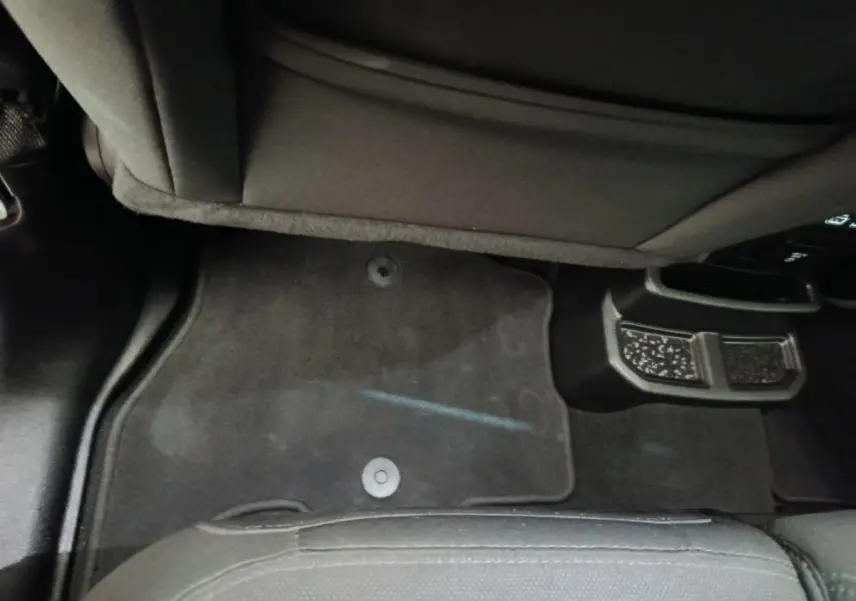 Vue intérieure du plancher arrière gris foncé de la Jeep Wrangler 2022 avec tapis de sol et partie inférieure des sièges noirs.