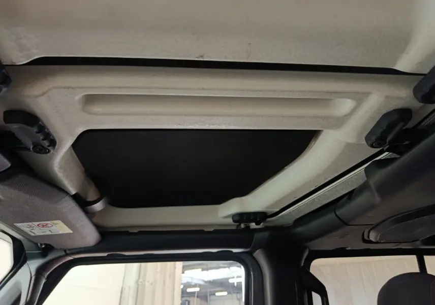Vue intérieure du toit cabriolet manuel beige et noir du Jeep Wrangler gris foncé 2022, côté conducteur.
