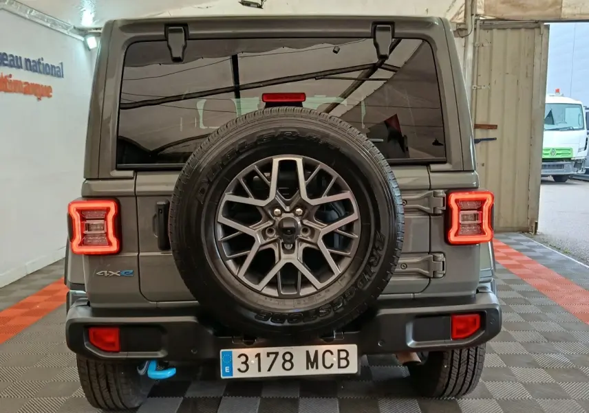 Vue arrière d'un Jeep Wrangler gris foncé avec roue de secours centrale et feux arrière LED en forme de C.