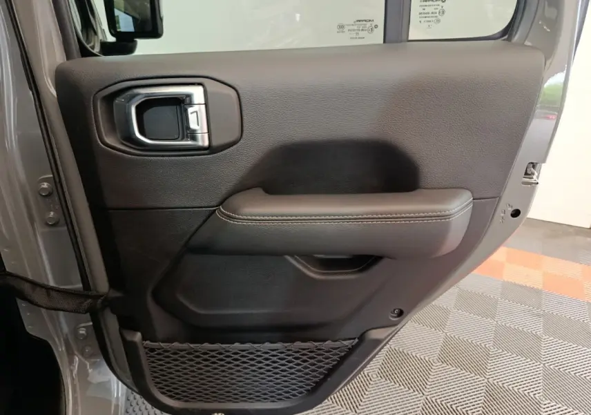 Vue rapprochée de la porte arrière droite gris foncé du Jeep Wrangler 2022, avec poignée intérieure et filet de rangement.
