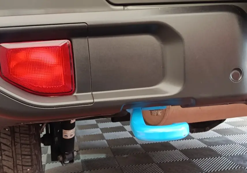 Gros plan sur l'attelage bleu sous le pare-chocs arrière gris foncé du Jeep Wrangler 2022, avec feu arrière rouge visible.