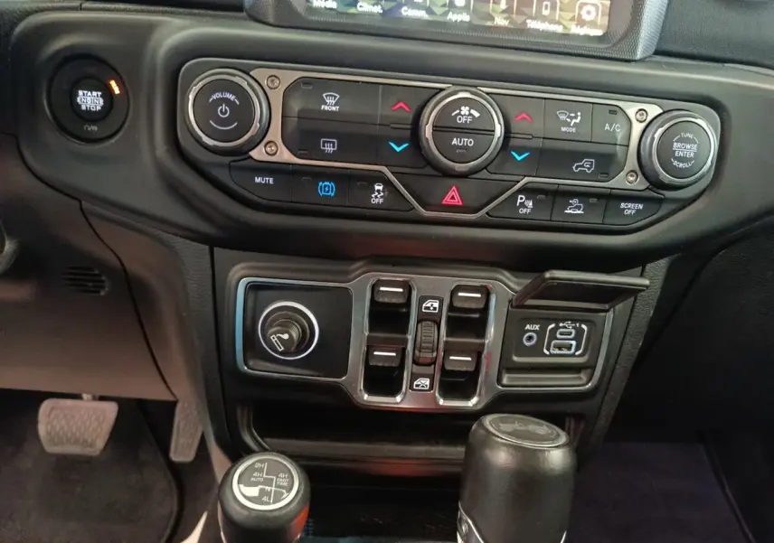 Vue rapprochée du tableau de bord central et console de la Jeep Wrangler 2022, avec commandes climatisation et leviers 4x4.