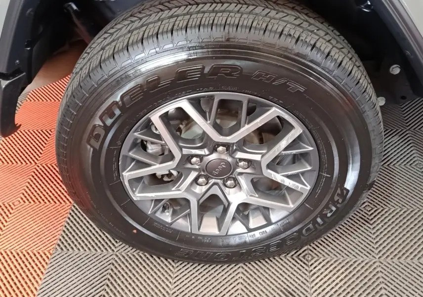 Gros plan sur la roue avant droite gris foncé d’un Jeep Wrangler 2022 avec jante alliage et pneu Bridgestone Dueler.