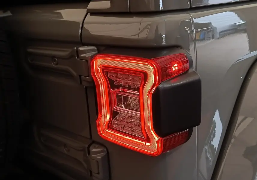 Gros plan sur le feu arrière droit rouge d’un Jeep Wrangler gris foncé 2022, avec charnières visibles sur la porte arrière.