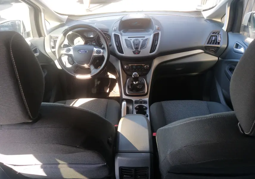 Vue intérieure avant du Ford C-MAX blanc 2013, montrant le tableau de bord, volant multifonction et levier de vitesse manuel.