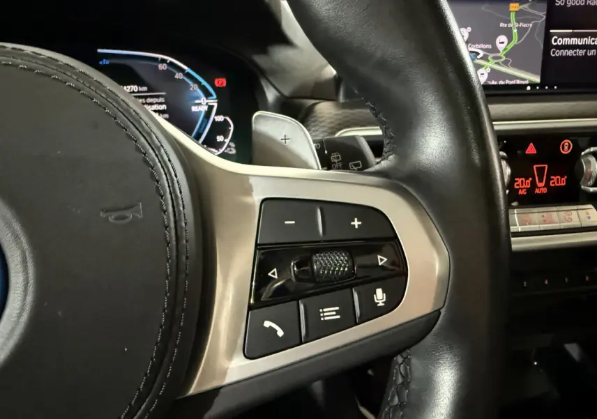 Gros plan sur les commandes multifonctions à droite du volant cuir noir du BMW X3 xDrive30e bleu, avec tableau de bord digital.