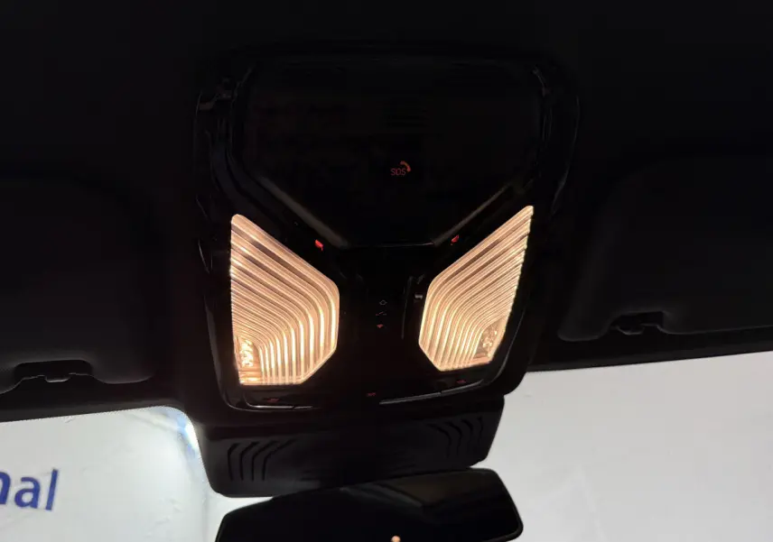 Plafonnier intérieur allumé vu de dessous dans un BMW X3 xDrive30e bleu 2023, avec bouton SOS rouge visible.