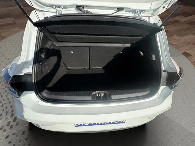 Coffre ouvert vu de l'arrière d'une Renault Clio V blanche, montrant l'espace de chargement vide et l'intérieur noir.