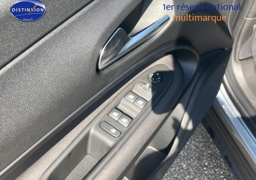 Vue rapprochée de la porte avant gauche grise de l'Alfa Romeo Junior 1.2 hybride, avec commandes électriques et haut-parleur intégré.