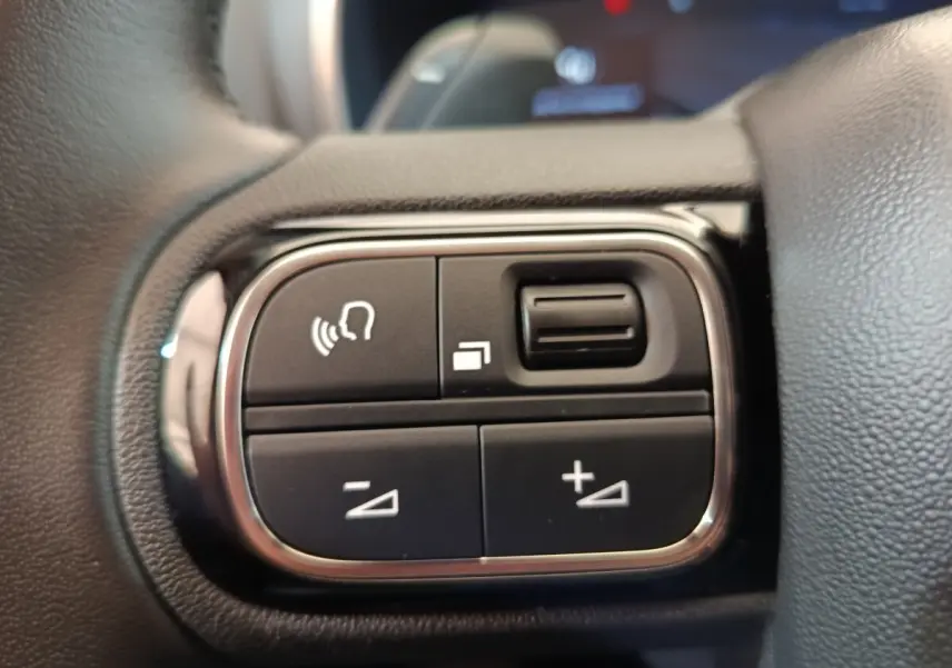 Gros plan sur les commandes vocales et volume au volant cuir noir du Citroën C5 Aircross 2024.