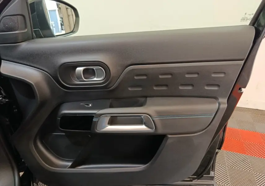 Vue intérieure de la porte arrière droite noire du Citroën C5 Aircross 2024 avec poignée argentée et surpiqûres bleues.