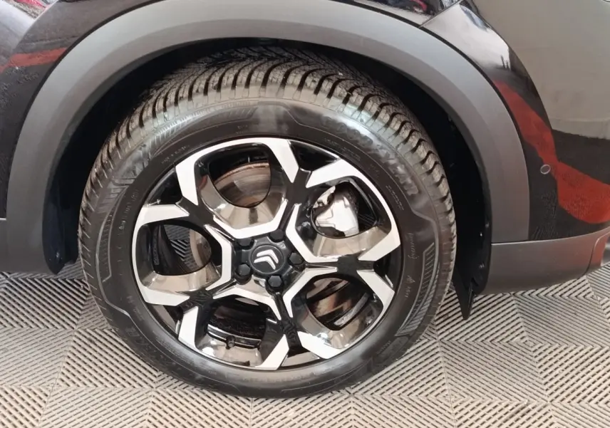 Gros plan sur la roue arrière droite noire du Citroën C5 Aircross 2024 avec jante alliage bicolore distinctive.