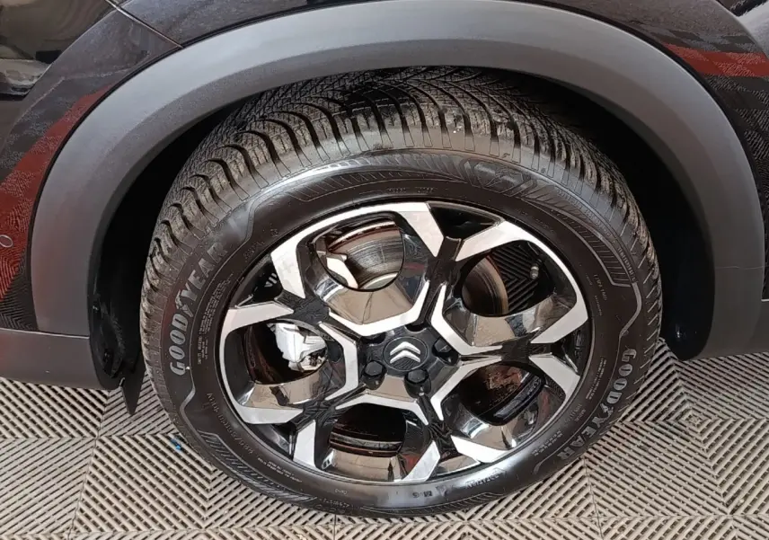 Gros plan sur la roue avant gauche noire du Citroën C5 Aircross 2024 avec jante alliage bicolore et pneu Goodyear.