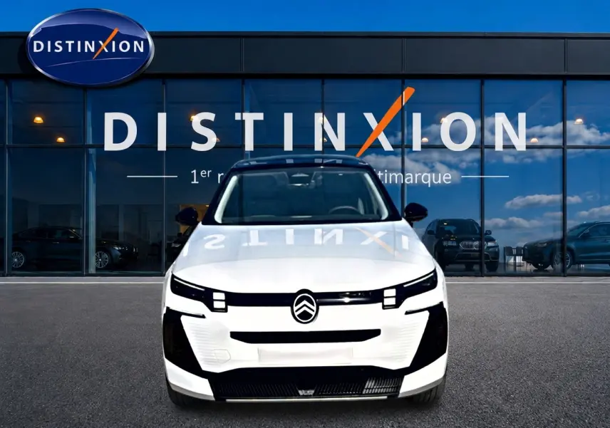 Vue frontale d'un Citroën C5 Aircross 2026 blanc avec toit noir, devant une vitrine au logo Distinxion.