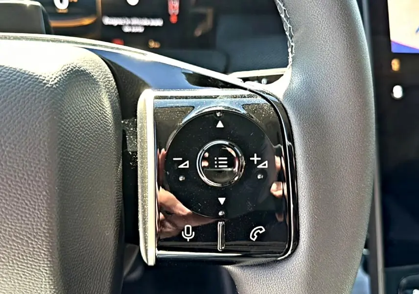 Gros plan sur les commandes gauche du volant noir du Citroën C5 Aircross hybride blanc/noir de 2026.