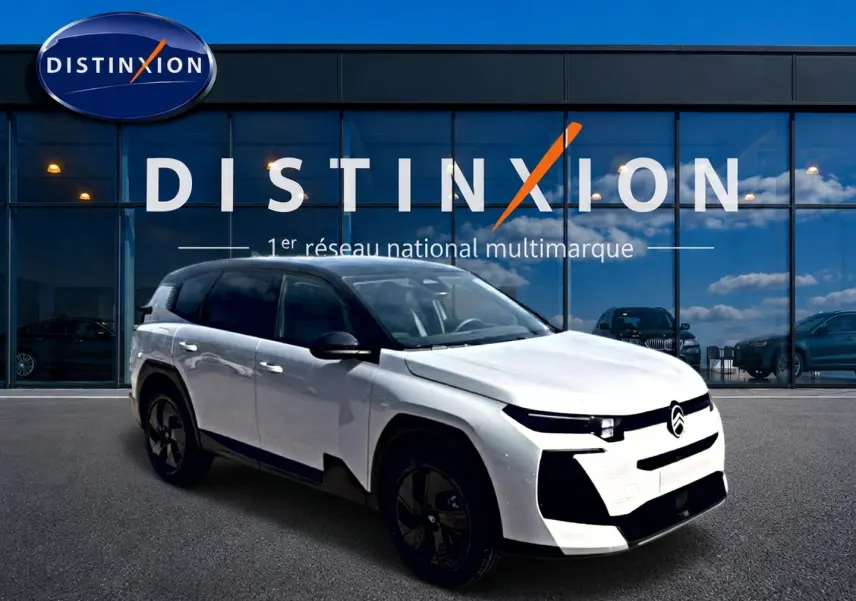 Vue 3/4 avant d'un Citroën C5 Aircross blanc à toit noir, avec jantes alliage noires, devant une vitrine Distinxion.