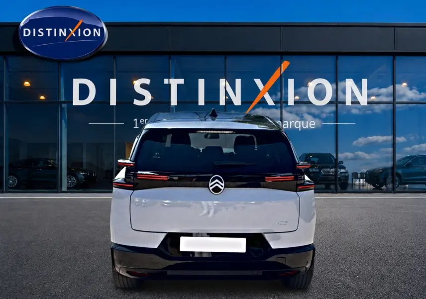 Vue arrière d'un Citroën C5 Aircross blanc et noir avec feux arrière LED, garé devant une vitrine Distinxion.