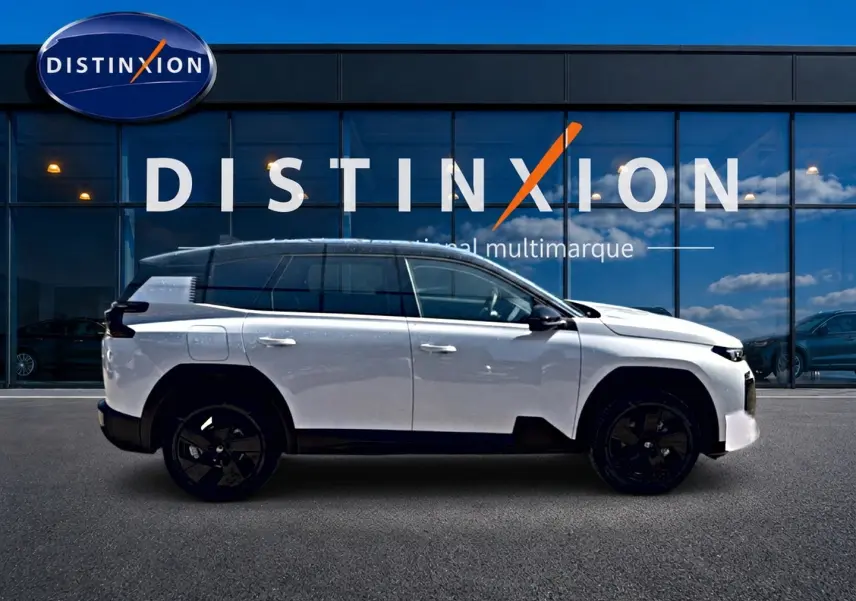 Profil droit du Citroën C5 Aircross hybride blanc avec toit noir et jantes alliage noires devant une vitrine Distinxion.