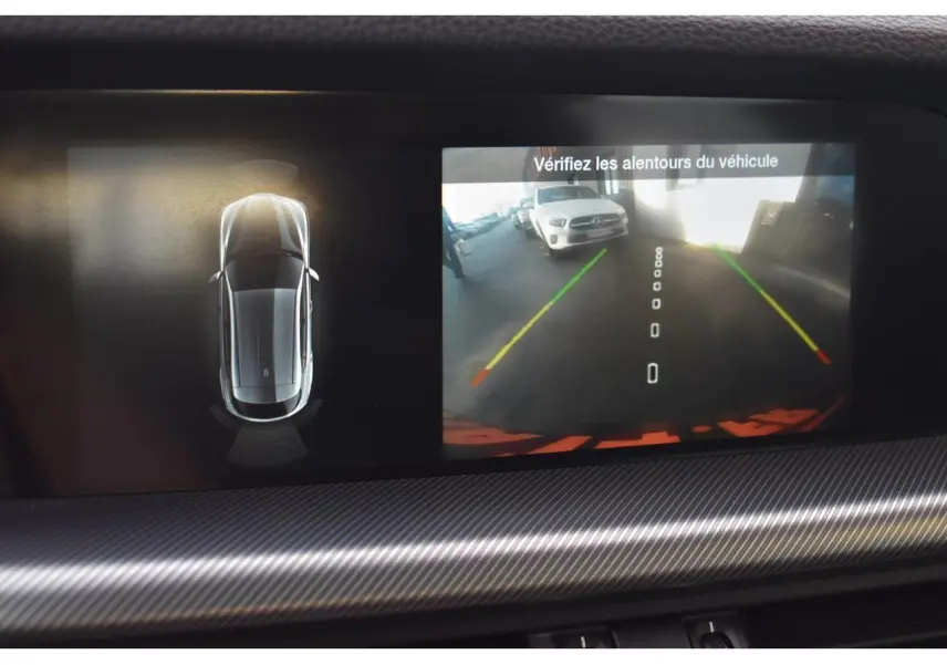 Écran intérieur montrant la caméra de recul et la vue 360° du SUV Alfa Romeo Stelvio gris Vesuvio en stationnement.