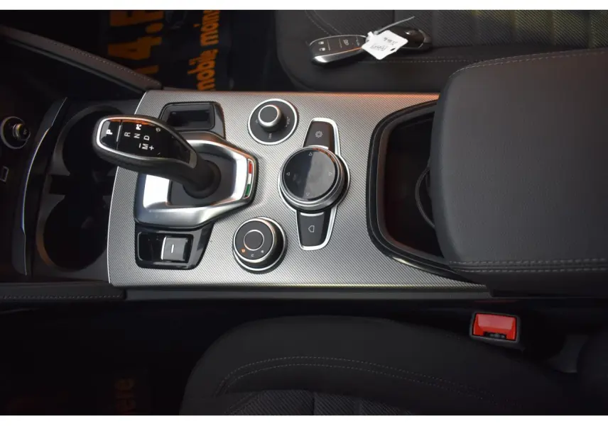 Vue rapprochée de la console centrale de l'Alfa Romeo Stelvio 2024, avec levier de vitesse et commandes circulaires.